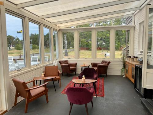a screened in porch with tables and chairs and windows at Böda Hotell in Böda