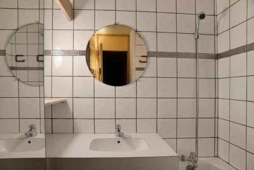 La salle de bains est pourvue de carrelage blanc, d'un lavabo et d'un miroir. dans l'établissement Résidence Saint Jacques A - Studio pour 4 Personnes 19, à Mâcot La Plagne
