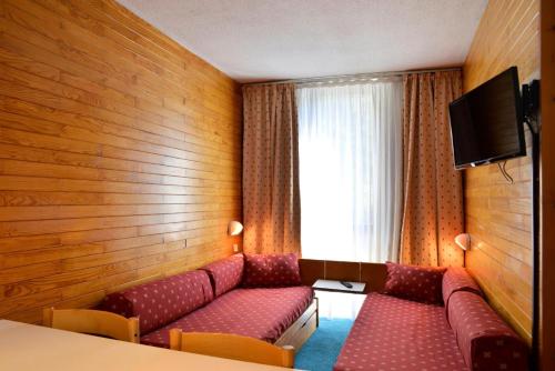 une chambre d'hôtel avec un canapé et une fenêtre dans l'établissement Résidence Saint Jacques A - Studio pour 4 Personnes 19, à Mâcot La Plagne