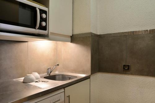 une cuisine avec un évier et un micro-ondes dans l'établissement Résidence Saint Jacques A - Studio pour 4 Personnes 19, à Mâcot La Plagne