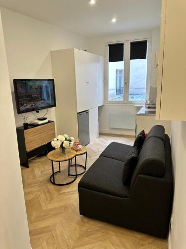 un salon avec un canapé noir et une télévision dans l'établissement Studio Champs Elysées Tour Eiffel, à Paris