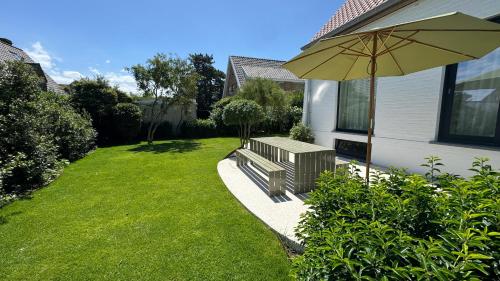 a garden with a bench and an umbrella at House W - North Sea Stays in De Haan