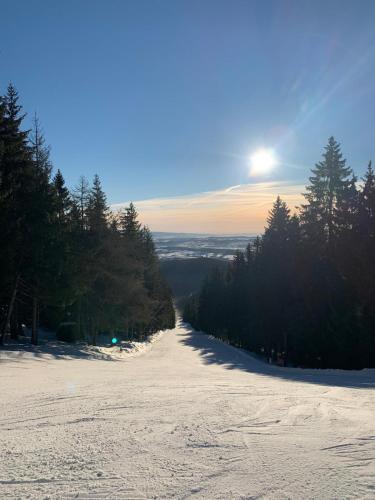 a snow covered hill with the sun in the background at Apartmán Jestřáb Janské Lázně in Janske Lazne