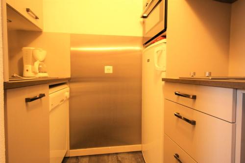 une petite cuisine avec un réfrigérateur et un micro-ondes dans l'établissement Résidence La Traverse - Appartement duplex situé en centre station MAE-9024, à La Plagne Tarentaise