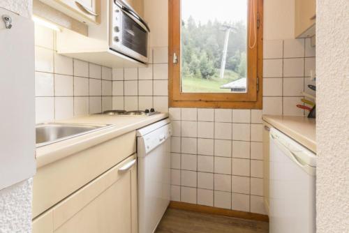 une petite cuisine avec un évier et une fenêtre dans l'établissement Résidence Le De 1 - Bel appartement spacieux MAE-4534, à La Plagne Tarentaise