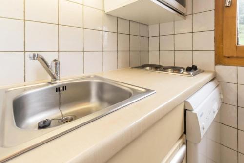 - un évier en acier inoxydable dans une cuisine carrelée de blanc dans l'établissement Résidence Le De 1 - Bel appartement spacieux MAE-4534, à La Plagne Tarentaise