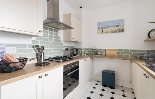 a kitchen with white cabinets and a stove top oven at Beautiful Sea Front Cottage in the Ocean City in Plymouth
