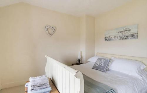 ein Schlafzimmer mit einem weißen Bett und einem Herz an der Wand in der Unterkunft Beautiful Sea Front Cottage in the Ocean City in Plymouth
