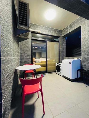 a room with a table and a red chair and a microwave at 萊恩晴旅包棟民宿 in Magong