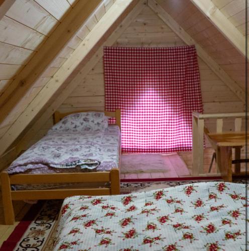 a attic room with two beds and a red wall at WildBeauty Grebaje in Vusanje