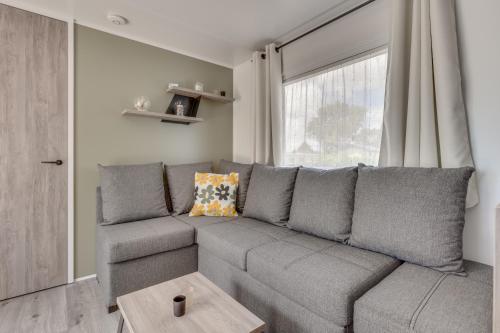 a gray couch in a living room with a window at Bondi Beach in Renesse