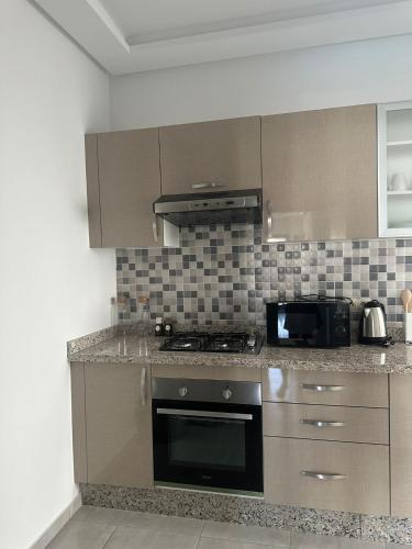 a kitchen with a stove and a microwave at Costa blanco Martil in Martil