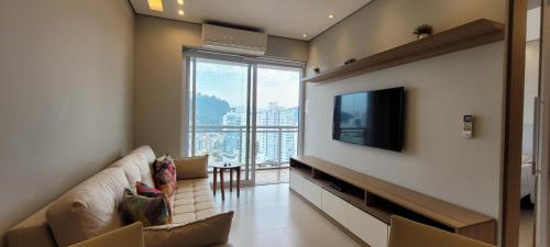 a living room with a couch and a flat screen tv at Book Santos - Unlimited 2111 Vista Mar in Santos