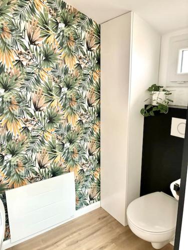 une salle de bain avec toilettes et un papier peint tropical dans l'établissement Aux Pierres Dorées 10 min centre de Lyon, à Pierre-Bénite