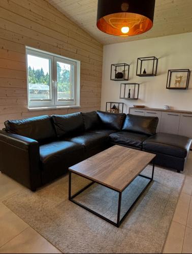 a living room with a black leather couch and a coffee table at Rezort Zvernica Vlachy - Family & Fun in Vlachy