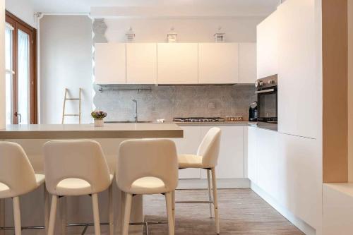 a kitchen with white cabinets and white chairs at Residenza l'Ulivo in Foiano della Chiana