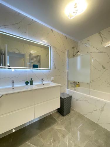 a bathroom with a sink and a mirror and a tub at PARIS PANTIN Magnifique Appartement 4 pièces de 108m2 avec 2 PARKING intérieur - très cosy pour 1 à 12 personnes - Entièrement refait à neuf ENTIRE APARTMENT LUXURIOUS AND WARM - PANTIN PARIS 19 ème FREE WIFI GRATUIT in Pantin