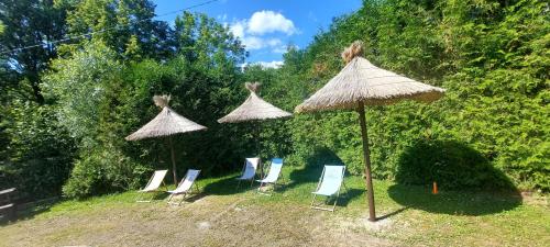 a group of chairs and umbrellas in a yard at WILLA NA WYŁĄCZNOŚĆ 12 os BIESZCZADY z Salą Imprezową, Jacuzzi, Sauną, Balią Zewnętrzną oraz 2 baseny z podgrzewaną wodą - Rezydencja Matiaszówka in Polańczyk