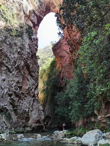 a person standing in a river under an arch in a mountain at El Sama' family house Rooftop 80m2 in Chefchaouene