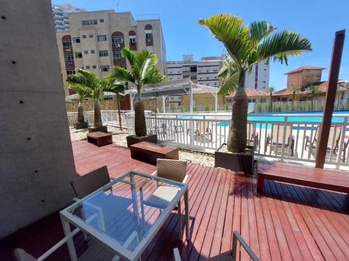 a deck with a glass table and chairs and palm trees at Book Santos - Unlimited 2111 Vista Mar in Santos