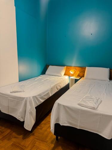 two beds in a room with a blue wall at Lamparina Hostel in Sao Paulo