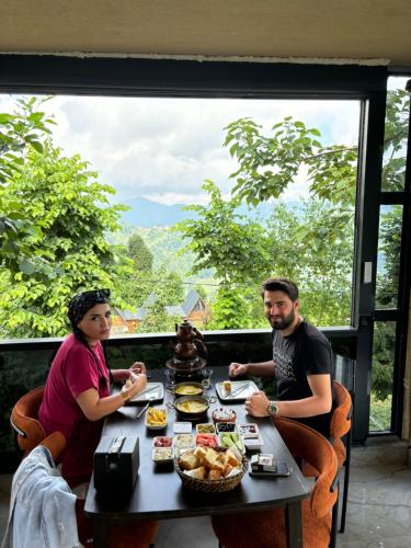 a man and a woman sitting at a table with food at Doğallife suit bungalow in Çamlıhemşin