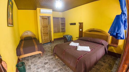 a bedroom with two beds in a yellow room at El Retiro Lanquin in Lanquín