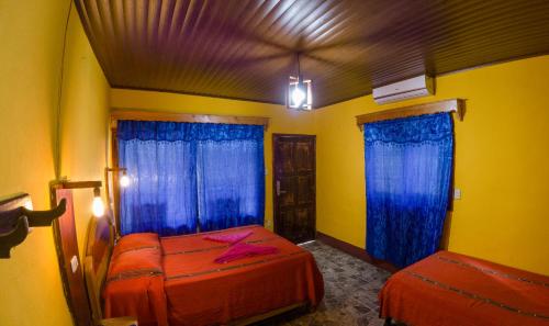 a bedroom with two beds and blue curtains at El Retiro Lanquin in Lanquín
