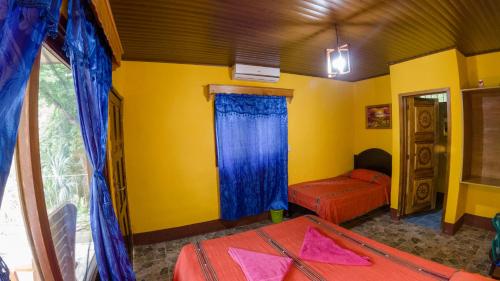 a bedroom with two beds and a yellow wall at El Retiro Lanquin in Lanquín