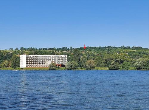 a large white building on the shore of a lake at Chalet Červená Veža in Banka