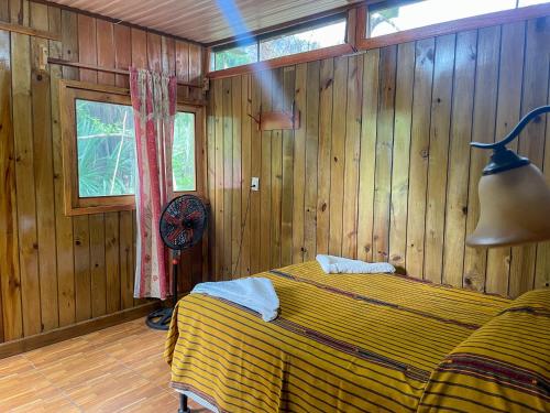 a bedroom with a bed in a room with wooden walls at El Retiro Lanquin in Lanquín