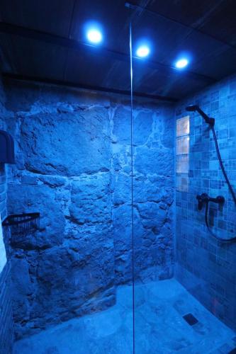 a bathroom with a glass shower with blue lights at La Porteria in Viladomíu Vella