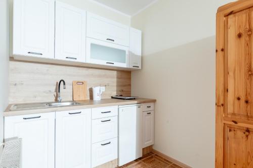 a kitchen with white cabinets and a sink at Pensjonat Jagódka in Trzęsacz