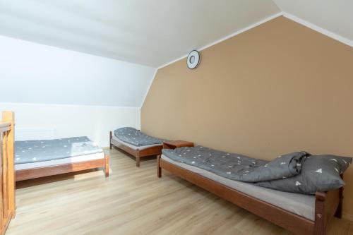 a room with two beds and a clock on the wall at Pensjonat Jagódka in Trzęsacz