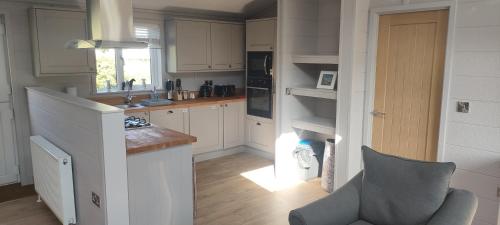 a kitchen with white cabinets and a chair in it at Great Trethew Hotel - Self Catering Lodges - Bar & Restaurant in Liskeard