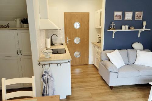 a living room with a couch and a kitchen at Ferienhaus Seeschwalbe - Alte Schmiede Neugarmssiel in Wangerland