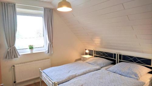 two beds in a bedroom with a window at Ferienhaus Seeschwalbe - Alte Schmiede Neugarmssiel in Wangerland