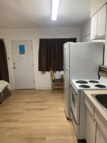 a kitchen with a stove and a white refrigerator at Swiss Sunset Inn in Penticton