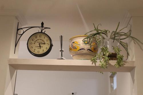 a shelf with a clock and a vase and a plant at Roma Casetta - Tourist Rooms in Guidonia