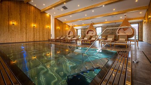 a pool in a hotel with chairs and tables at Hôtel SPA du Lac de Madine - Maison DRAPIER in Heudicourt-sous-les-Côtes