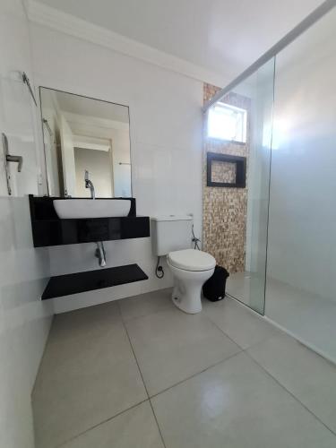 a bathroom with a toilet and a sink and a mirror at Residencial Costa Marfim in Bombinhas