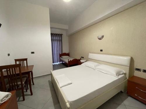 a bedroom with a white bed and a table and chairs at Hotel Latifi in Gramsh