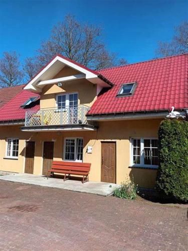 a house with a red roof and a bench at Pensjonat Jagódka in Trzęsacz