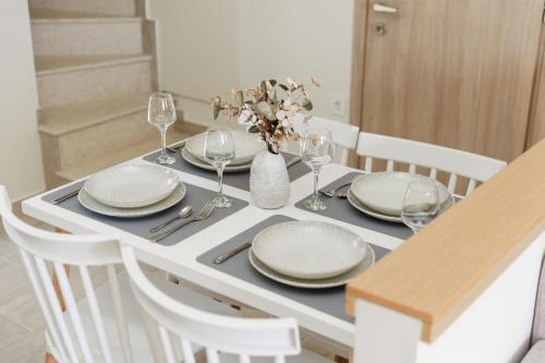 a table with plates and glasses and a vase with flowers at SeaSide Village in Politiká