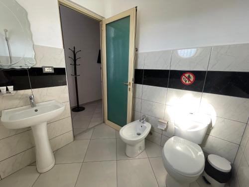 a bathroom with a sink and a toilet and a bidet at Hotel Latifi in Gramsh
