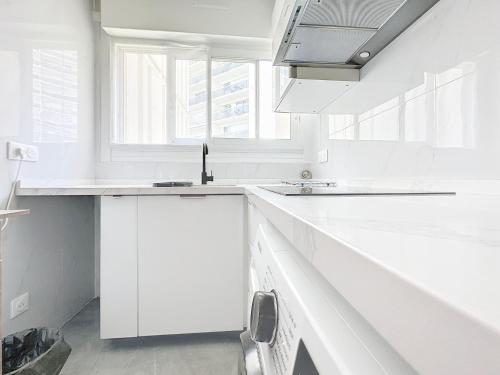 - une cuisine blanche avec des comptoirs blancs et un évier dans l'établissement 114 - Paris Appartement Rénové de Luxe pour 4 Personnes, à Paris