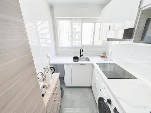une cuisine blanche avec un évier et une cuisinière dans l'établissement 114 - Paris Appartement Rénové de Luxe pour 4 Personnes, à Paris