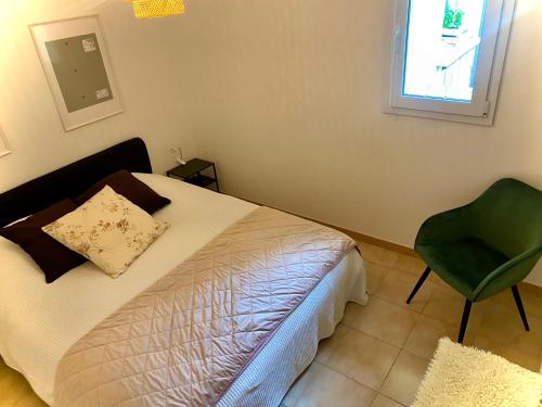 - une chambre avec un lit et une chaise verte dans l'établissement Au coin du pin, à Menton