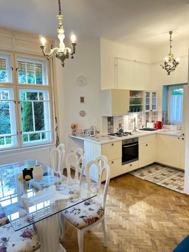 eine Küche mit einem Glastisch und weißen Stühlen in der Unterkunft Heritage Harmony with FREE PARKING in Budapest