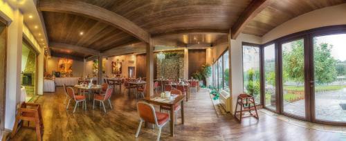 comedor con mesas y sillas y ventanas grandes en Tselikas Hotel, en Kozani